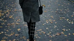 Žena kráčí po ulici pokryté podzimním listím