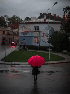 Žena kráčí po ulici s červeným deštníkem